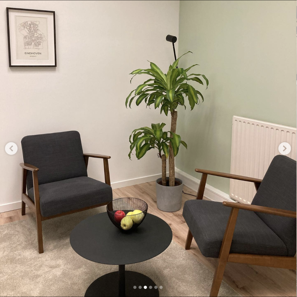 Gespreksruimte met lage stoelen, planten en wanddecoratie